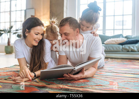 Parents and daughters reading picture book Stock Photo