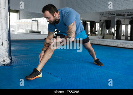 Mid adult man stretching in gym Stock Photo