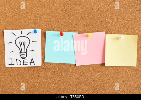 painted light bulb with word idea and colored blank notes on cork board Stock Photo