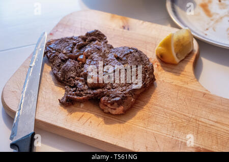 Medium rare Beef grilled with lemon slice on wooden chopping block Stock Photo