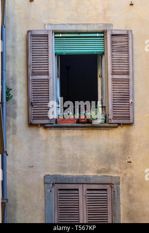 Windows with shutters on facade of residential building with flowers on it in Bergamo. Italy Stock Photo