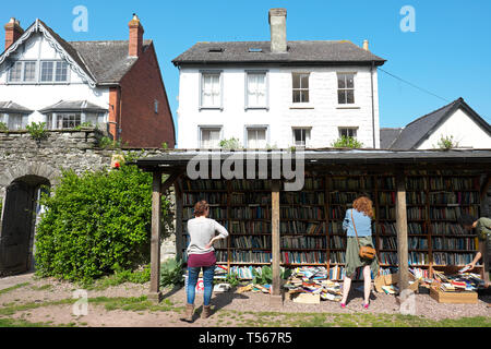 Hay on Wye Powys Wales - visitors browse the secondhand books for sale at the outdoor castle honesty bookshop in April 2019 Stock Photo