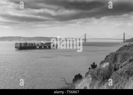 Moody Black and White Photo Of The Container Ship, MSC ARIANE, Steaming Through San Francisco Bay Towards The Golden Gate Bridge, California, USA. Stock Photo