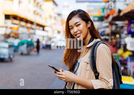 Young Asian female tourist woman using a mobile phone in Bangkok, Thailand. Calling a cab or finding information during traveling concept Stock Photo