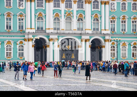 Unidentified tourists waiting in line at the entrance of the State Hermitage Museum at the Palace Square on a rainy day. Saint Petersburg, Russia. Stock Photo