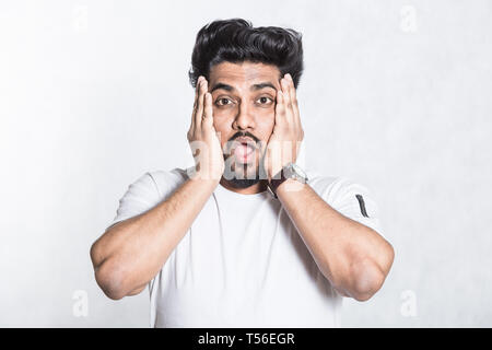Amazed young man looks with horror and panic, being shocked to hear bad news. Stock Photo