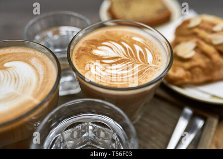 Milk coffee with croissant and bread and water on wooden table Stock Photo