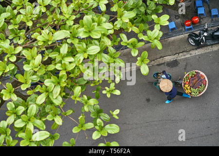 Person in asian bamboo hat walking with bananas on bike outdoors Stock Photo