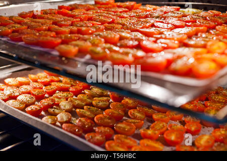 Trays of fresh cherry tomatoes on racks drying in the oven Stock Photo