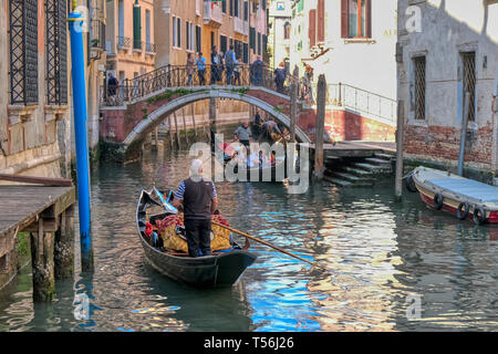 Venice, Italy - April 17 2019: Traditional Venetian Gondola boat with tourists in the narrow canals of Venice