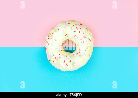 White round doughnut on pink and blue background. Flat lay, top view. Stock Photo