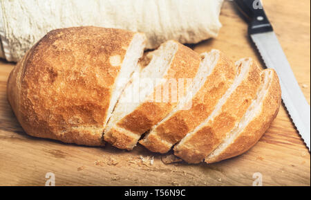 Ciabatta bread loaf slices on wooden board with knife. Fresh crusty white whreat bread italian cuisine Stock Photo