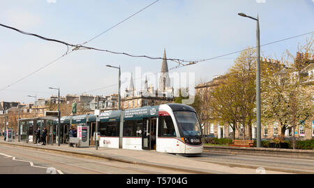 An Urbos 3 tram at the West End - Princes Street light railway station with Coates Terrace, the William Gladstone Monument and St Mary's Cathdral in t Stock Photo