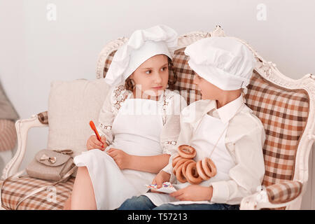 brother and sister in chef's caps discuss the lunch menu.Hobbies and interests Stock Photo