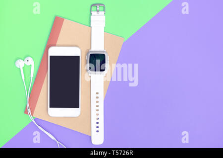 Empty mobile phone with smartwatch gadgets on green purple copy space Stock Photo