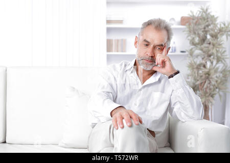 dreamy adult businessman sitting on sofa in office. Stock Photo