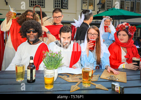 London, UK, 21th April 2019. The group of Jesus 'reincarnations' at one of their first stops, where the last supper is duly re-inacted with a pint and pub food. Participants dressed as Jesus and other biblical and related figures, complete with fold-out musical crucifix take part in this annual alternative pub walk along a route of biblically named pubs, raising money for a charitable cause. Credit: Imageplotter/Alamy Live News Stock Photo