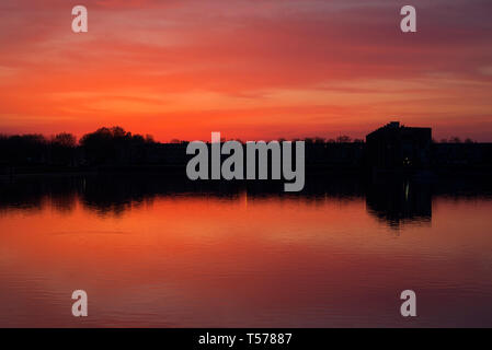 Paris, France. 21st Apr, 2019. Stunning sunset over the Lac de La Sourderie, in the south western Paris suburb of Montigny-le-Bretonneux. The view over-looks the residential area of Les Arcades du Lac, designed by Spanish architect Ricardo Bofill, and is known locally as ‘The Versailles for the People'. Credit: Francesca Moore/Alamy Live News Stock Photo