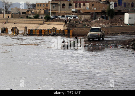 Sanaa, Yemen. 22nd Apr, 2019. People try to walk through a flooded road ...