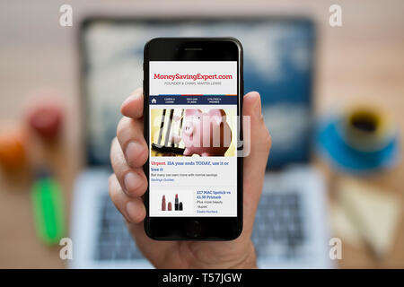 A man looks at his iPhone which displays the Money Saving Expert logo (Editorial use only). Stock Photo