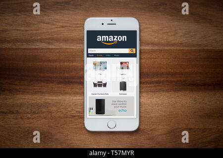 An iPhone showing the Amazon website rests on a yellow background table ...
