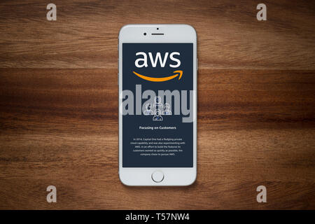 An iPhone showing the Amazon Web Services (AWS) website rests on a plain wooden table (Editorial use only). Stock Photo