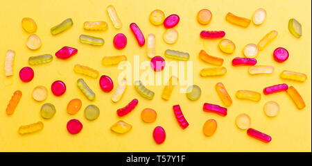 Jelly candies assortment on yellow color background, top view. Kids birthday party concept Stock Photo