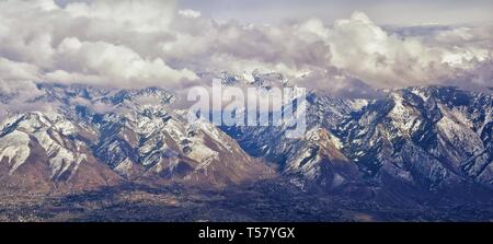 Aerial view from airplane of the Wasatch Front Rocky Mountain Range with snow capped peaks in winter including urban cities of Provo, Farmington Bount Stock Photo