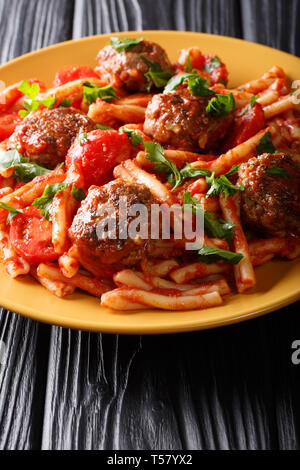 Tasty pasta Casarecce with meatballs in tomato sauce close-up on a plate on the table. vertical Stock Photo