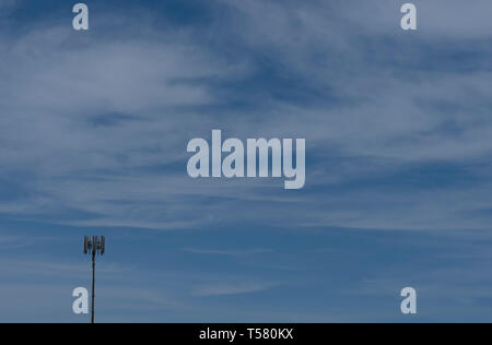 Cell phone tower set against large blue sky background Stock Photo