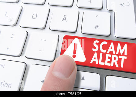 close-up of finger pressing red key labeled SCAM ALERT on computer keyboard Stock Photo