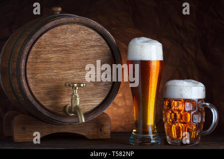 Beer barrel with two beer glasses on wooden table dark still-life Stock Photo