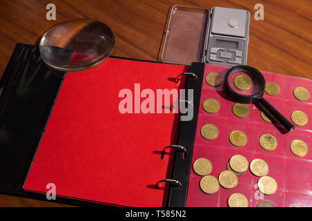 Various coins on a wooden table with magnifying glass Stock Photo