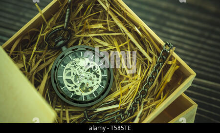 Pocket watch winder on natural wheat straw in a wooden box. Concept of vintage or retro gift. Stock Photo