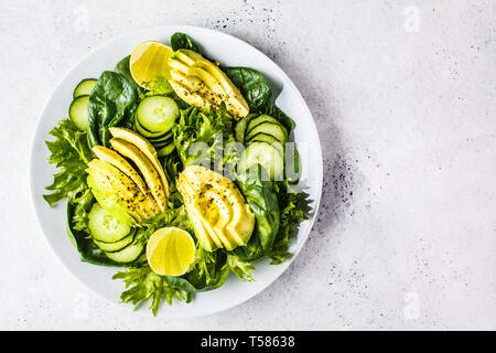 Green avocado and cucumber salad in a white plate. Detox menu, vegan food, plant based diet. Stock Photo