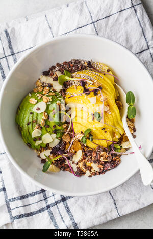 Granola with avocado, superfoods, berries and fruits in a white bowl. Plant based diet concept. Stock Photo