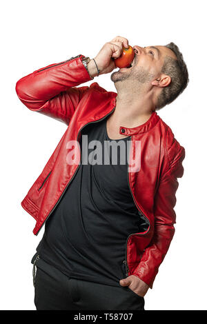 A man with open mouth in stylish clothes bites into an apple while he puts his head back Stock Photo