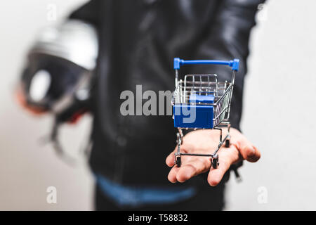 Delivery man standing and holding a mini shopping cart - The delivery service concept - Stock Photo