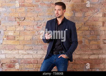 A serious handsome young businessman using his smartphone in a suit. Stock Photo