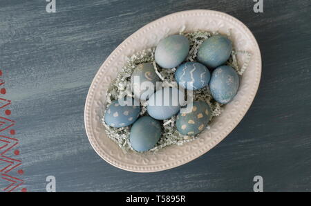 Painted Easter eggs, coloured with dye from red cabbage, on a chalk painted blue distressed wood table Stock Photo
