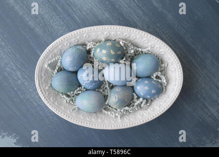 Painted Easter eggs, coloured with dye from red cabbage, on a chalk painted blue distressed wood kitchen table Stock Photo