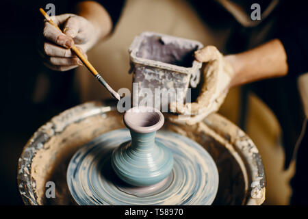 Man painting handmade pottery at ceramic workshop. Art concept Stock Photo