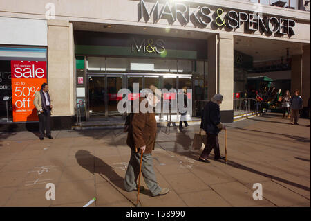 Elderly couple walking past Marks and Spencer. Oxford Street, London. 9/10/2008 Stock Photo