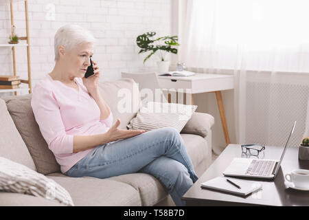 Angry senior woman complaining about problems with laptop Stock Photo