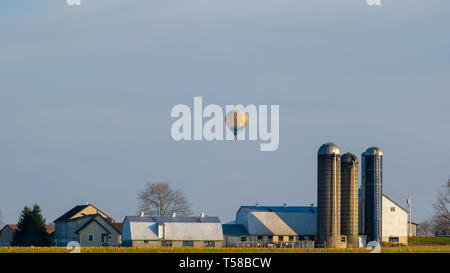 Hot air balloon traveling above an Amish farm house, Lancaster County, PA Stock Photo