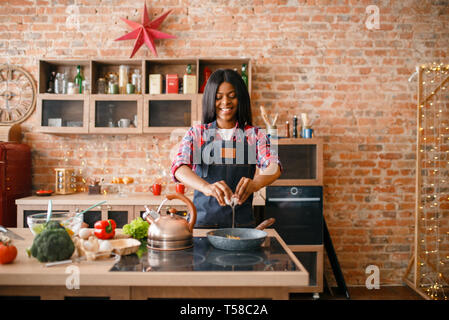 Black female person cooking fried eggs on kitchen Stock Photo