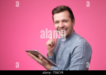 Pensive young man using his digital tablet and giving advice with index finger Stock Photo