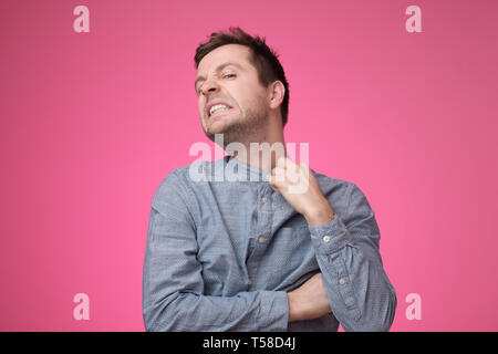 Frowning young businessman choking trying to put off his shirt. Stock Photo
