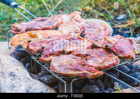 Outdoor grilling pork meat on charcoal grill fire Stock Photo