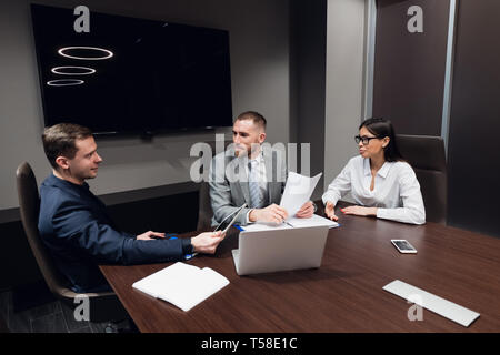 Startup business, creative business people of different age and races gather in meeting room in dark modern office interior, vivously discussing Stock Photo